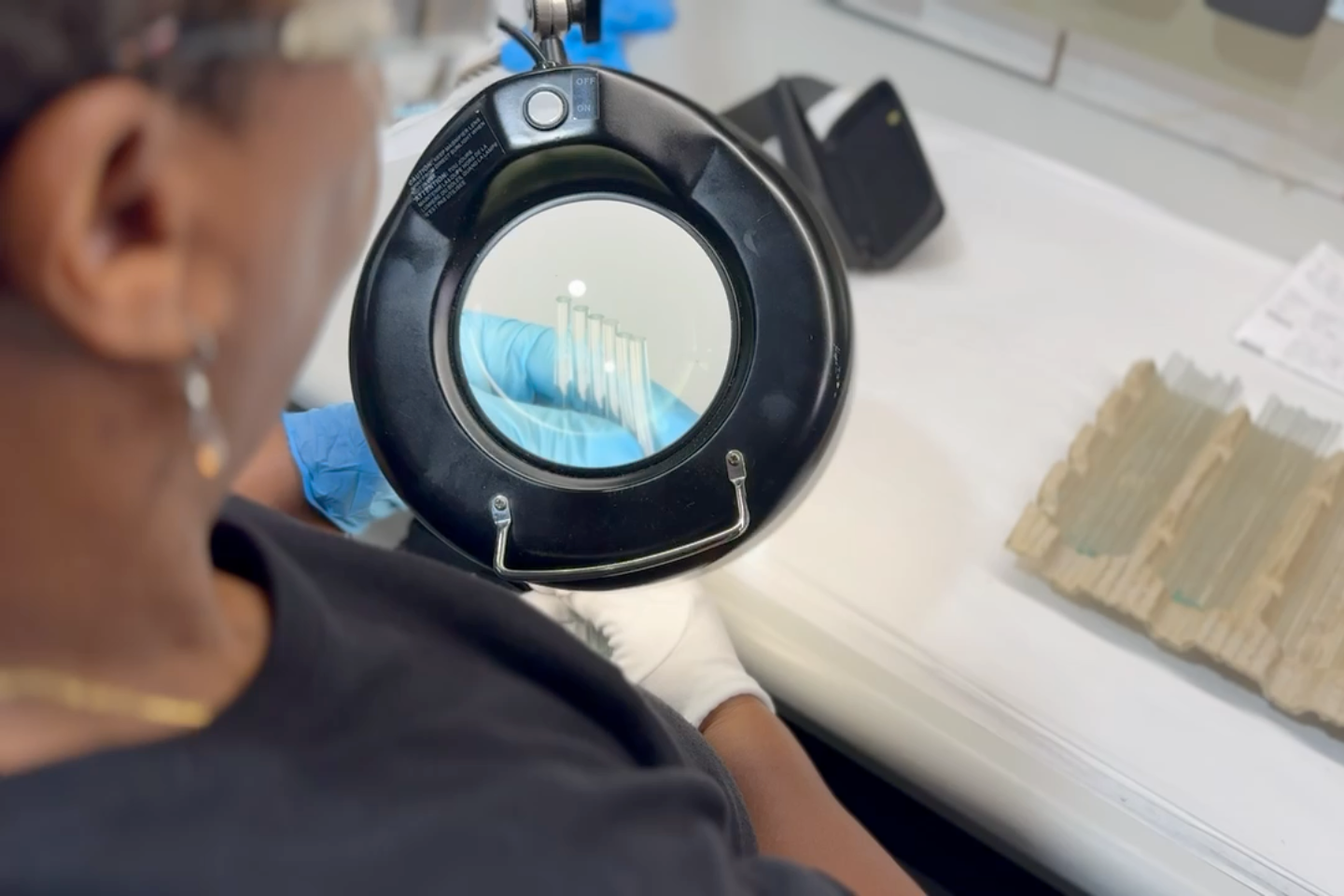 A person holds a handful of tubes underneath a magnifying glass.