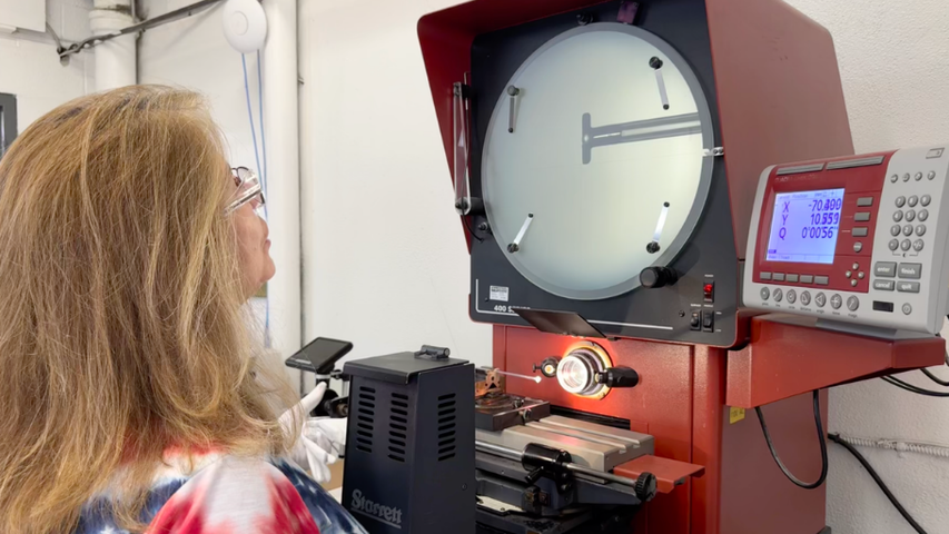A custom glass worker verifying the angle of a tube.